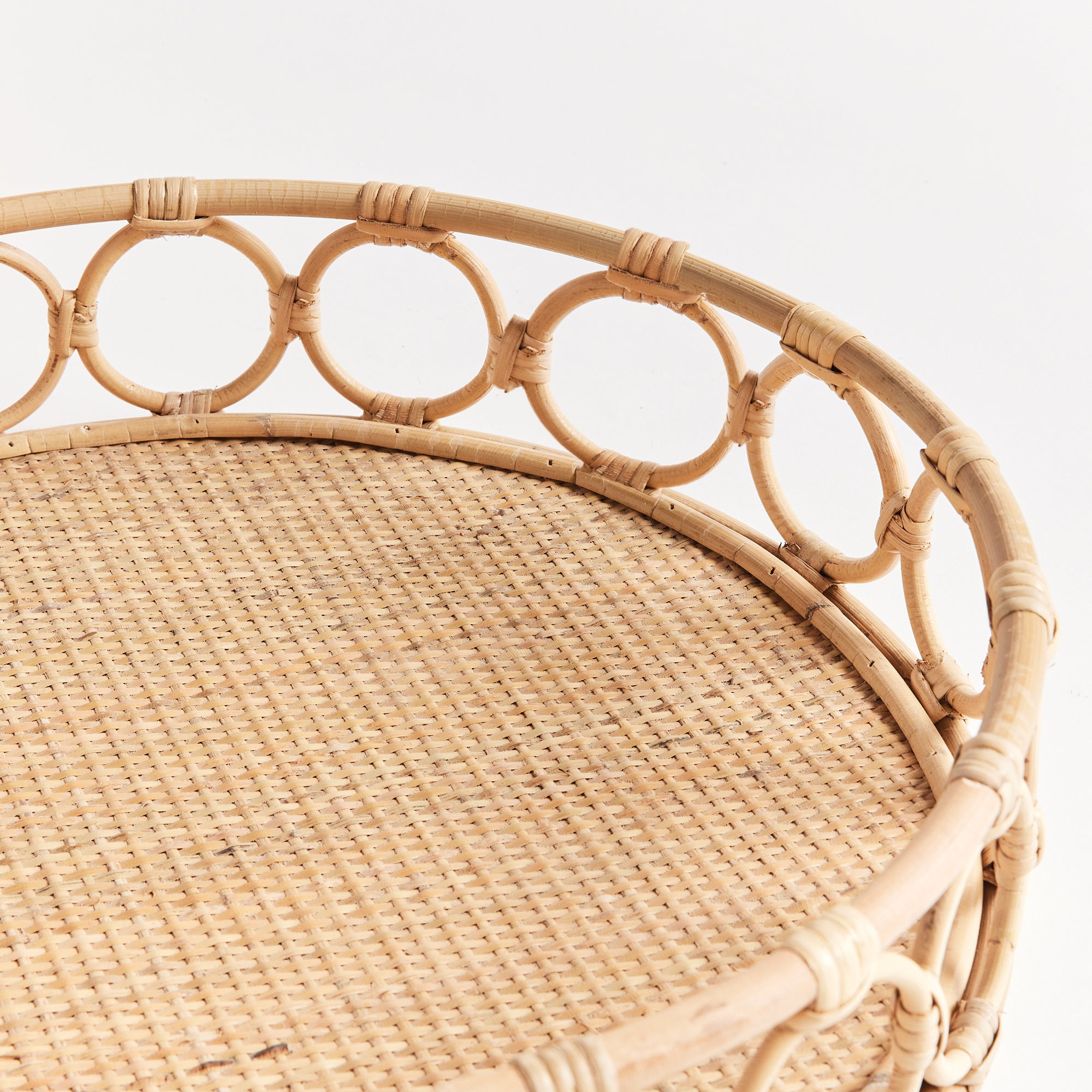Up close of circular woven tray with circles around edge on white background