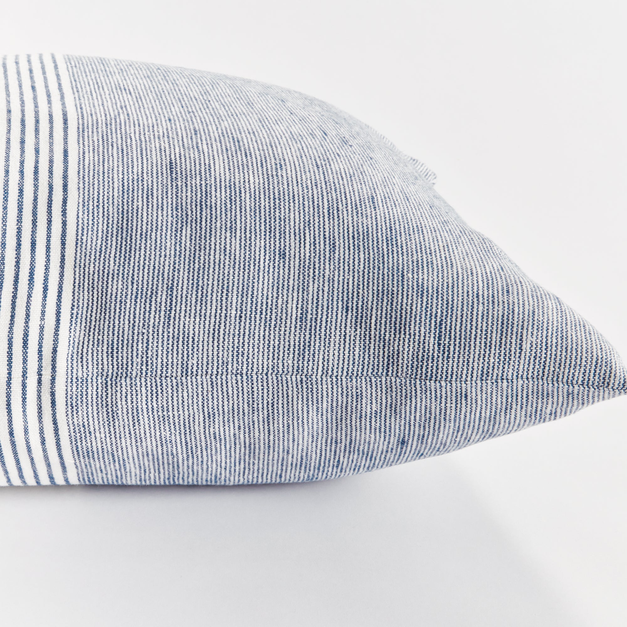 Close up of square pinstripe pillow in blue and white on a white background