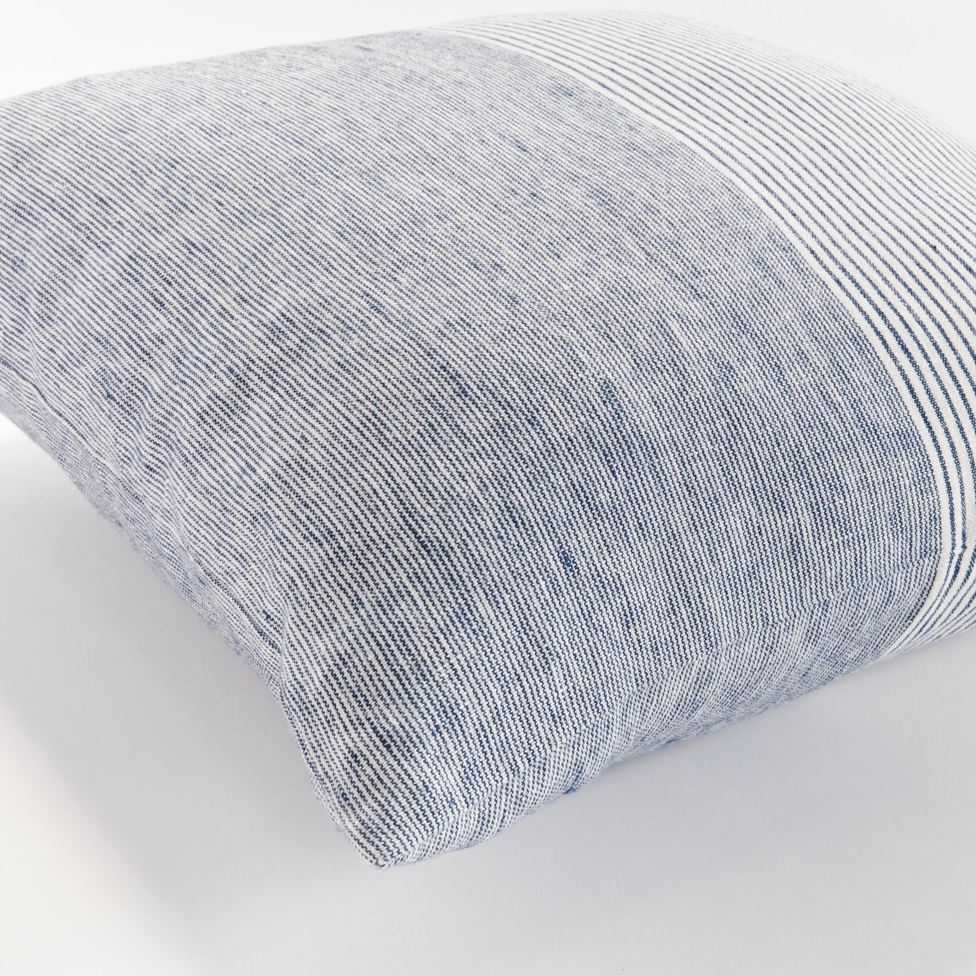 Close up of square pinstripe pillow in blue and white on a white background