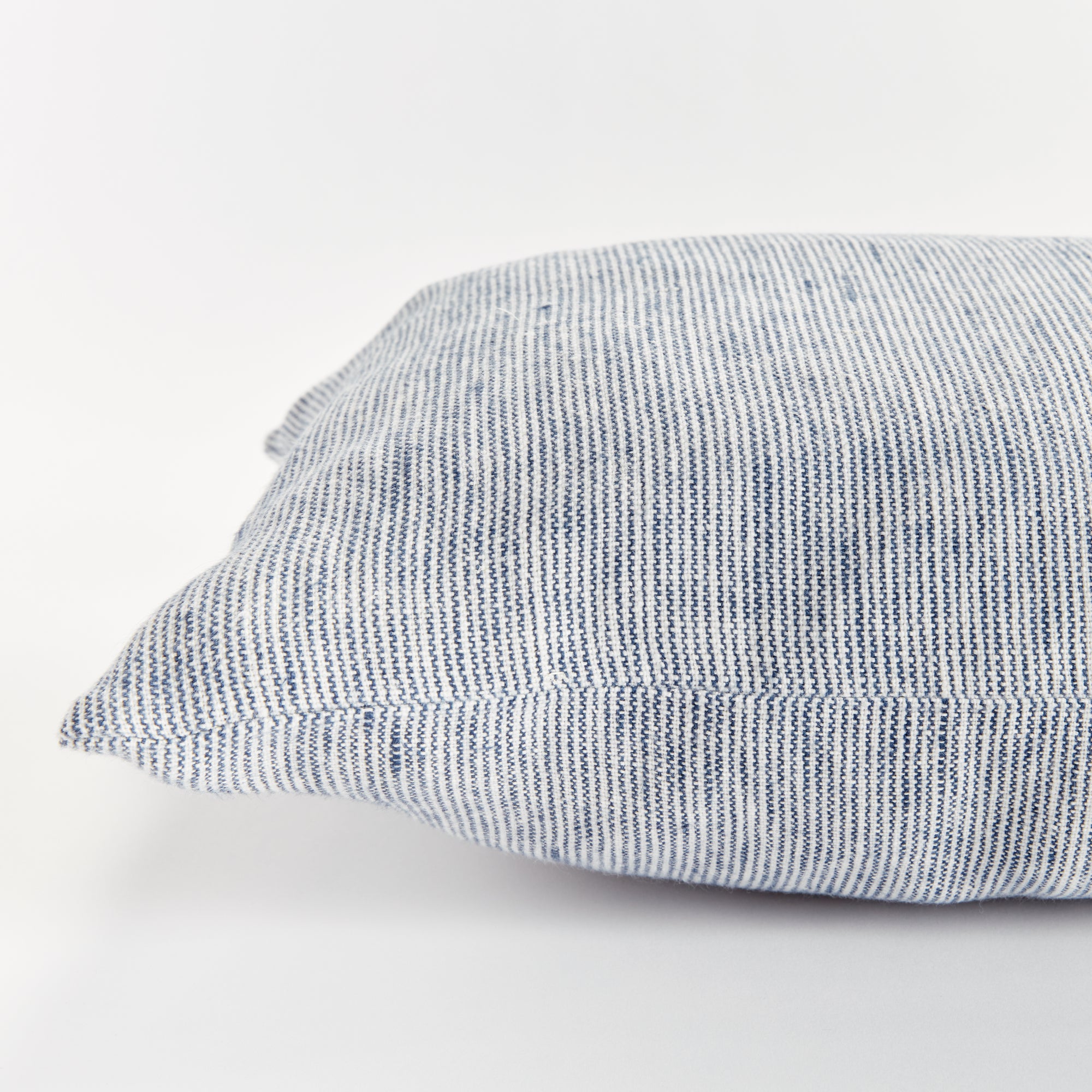 Close up of rectangular pillow with thin blue stripes on white background