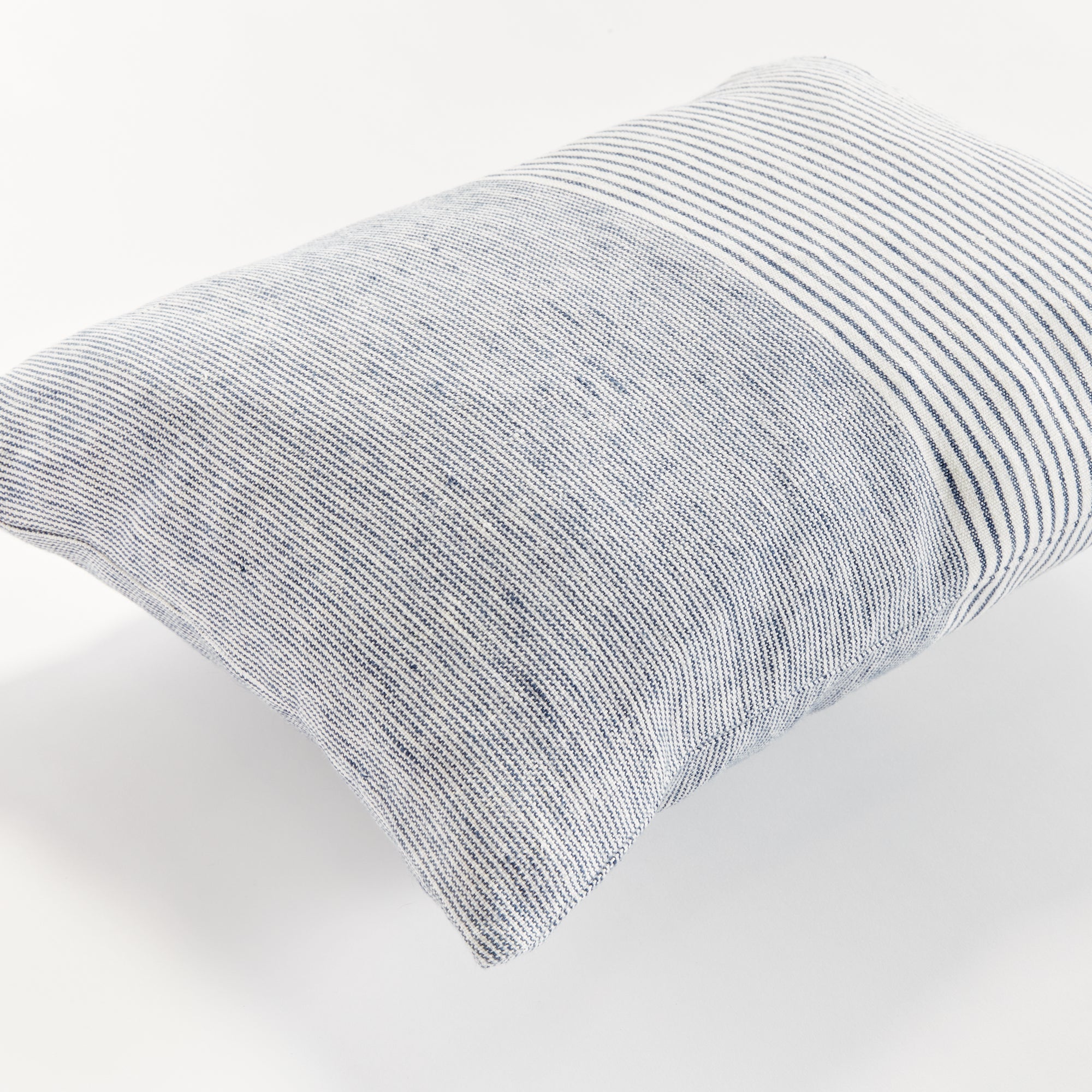 Close up of rectangular pillow with thin blue stripes on white background