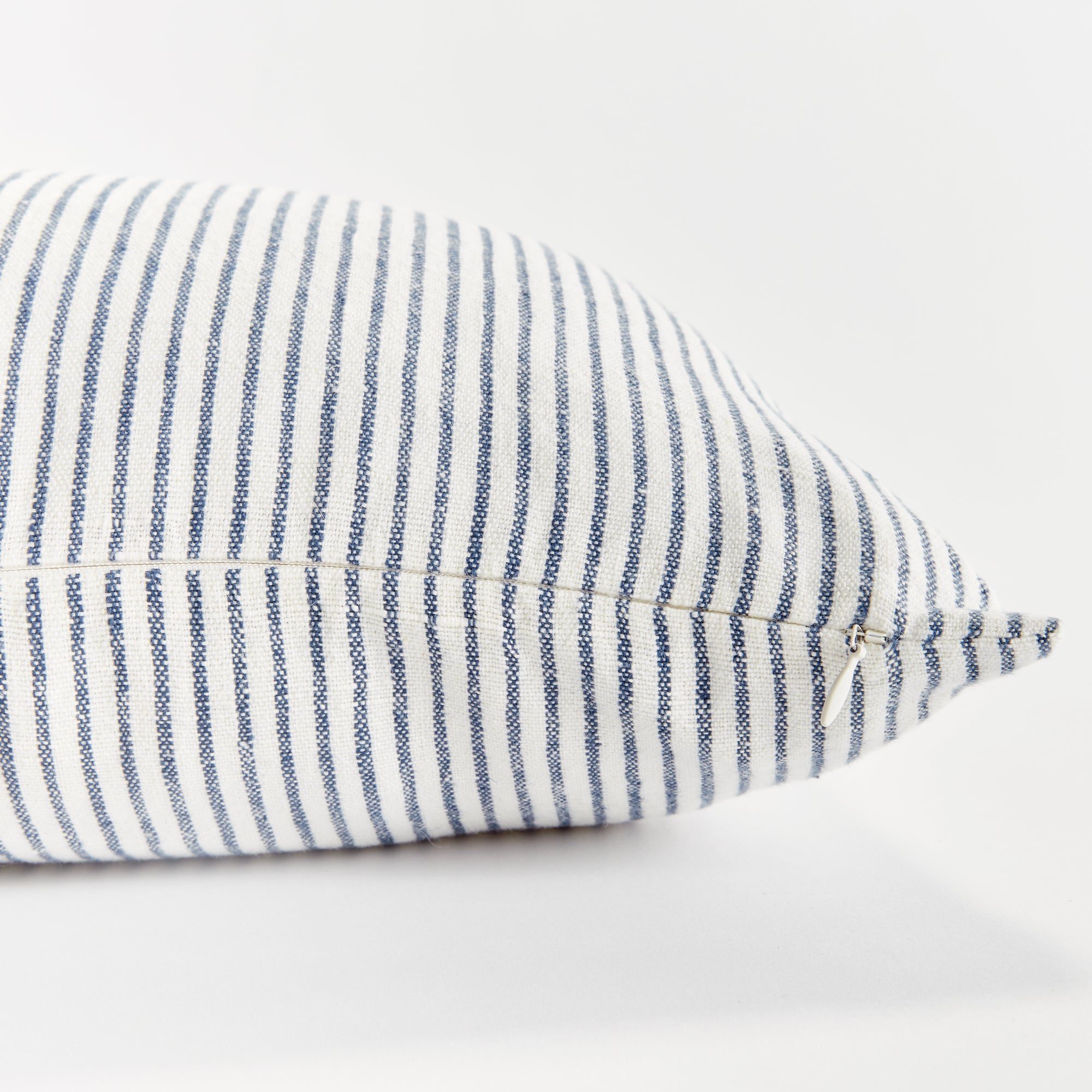 Close up of rectangular pillow with thin blue stripes on white background