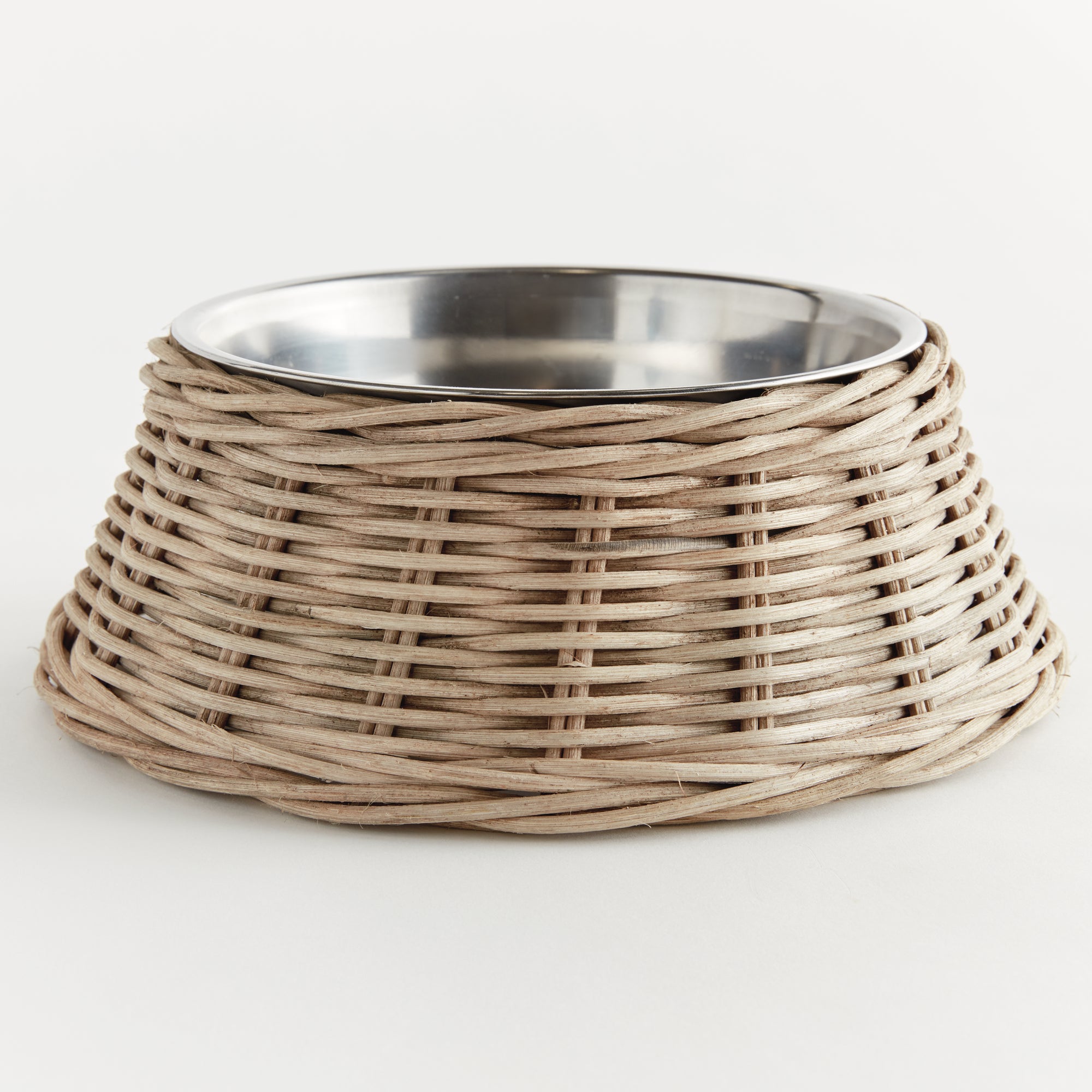 Wicker dog bowl with stainless steel insert on white background