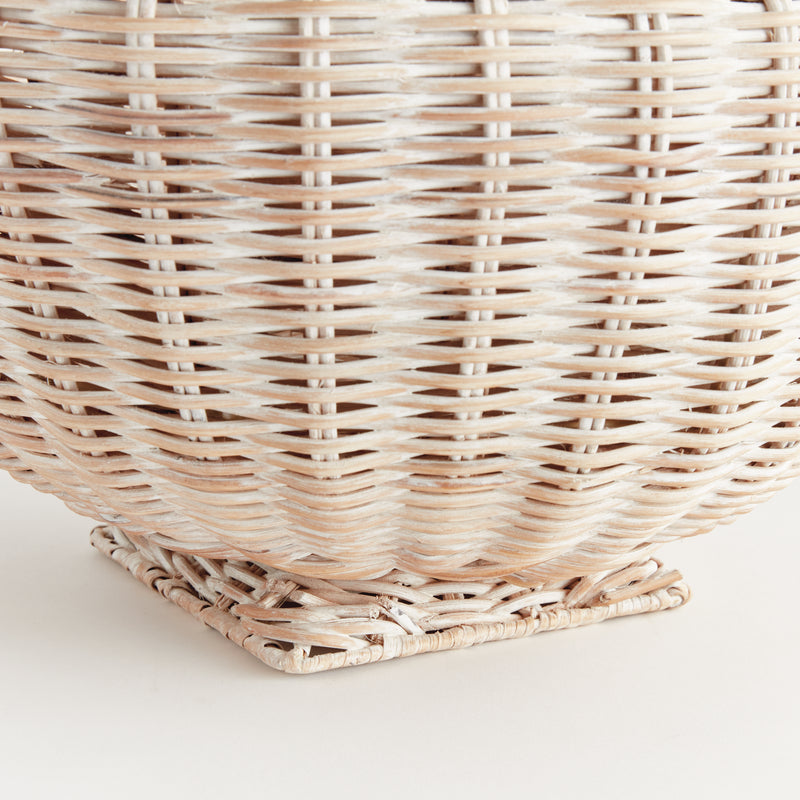 Close up of bottom of woven wicker bowl with square base on white background
