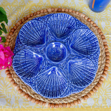 Blue ceramic dish with shell design on a woven mat