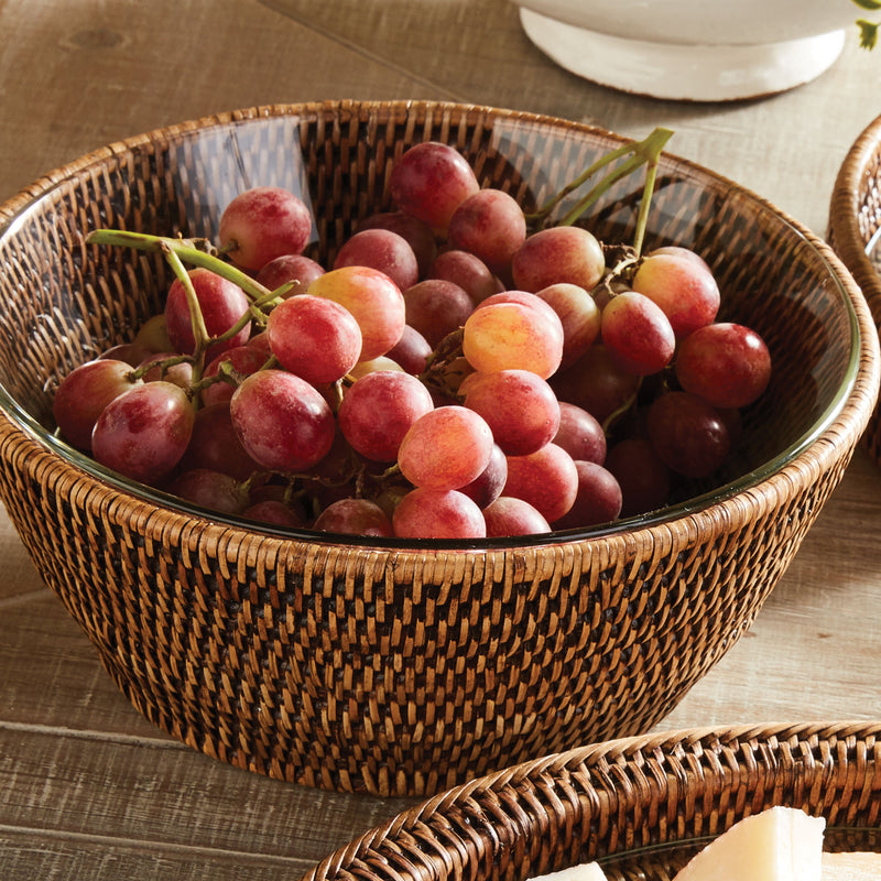 Rattan serving bowl with glass insert and grapes on brown table
