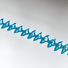 Close up of white sheet with turquoise embroidery
