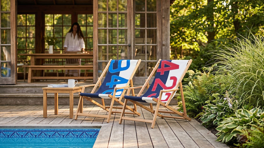 Two deck chairs with colorful designs on a wooden deck by a poolside.