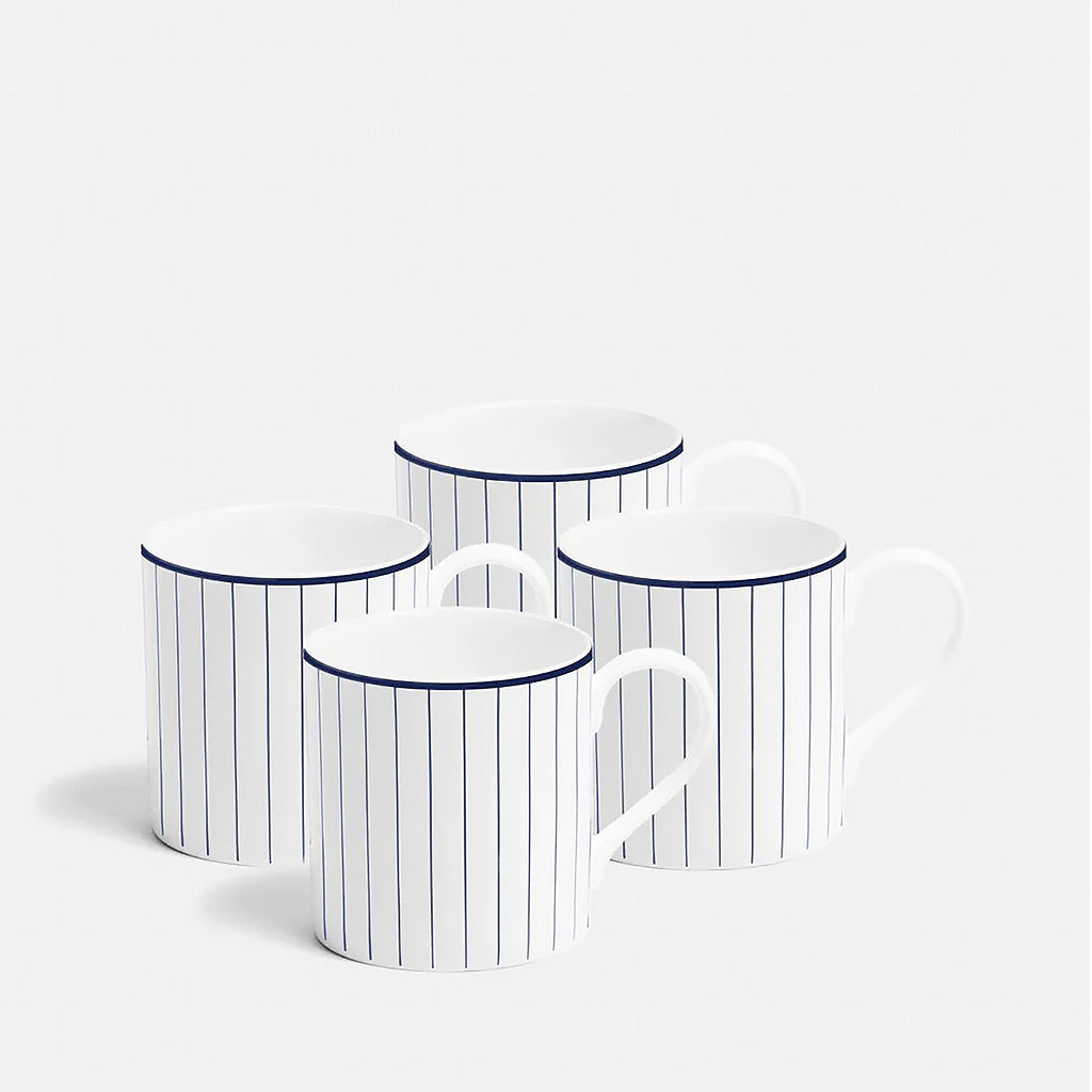 Set of four white mugs with blue stripes on a light gray background
