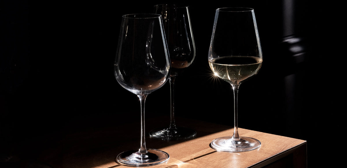 Two wine glasses on a wooden surface with a dark background