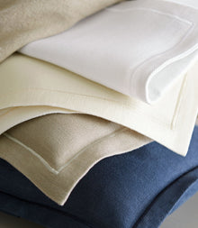 Stack of folded fabric swatches in beige, white, and blue.