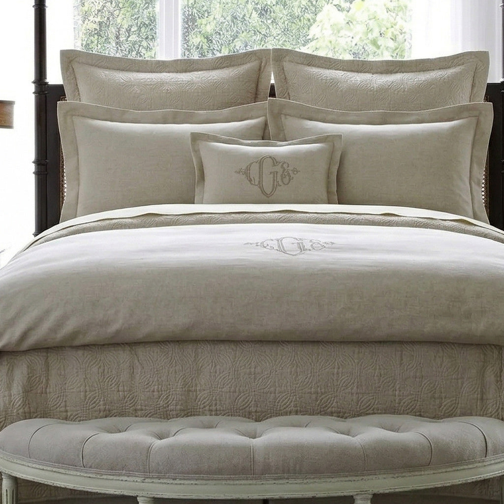 Neatly made bed with beige bedding and pillows in a bright room.