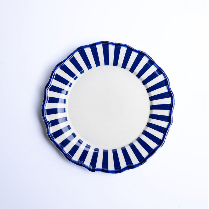 Ceramic plate with blue and white striped rim on a light gray background