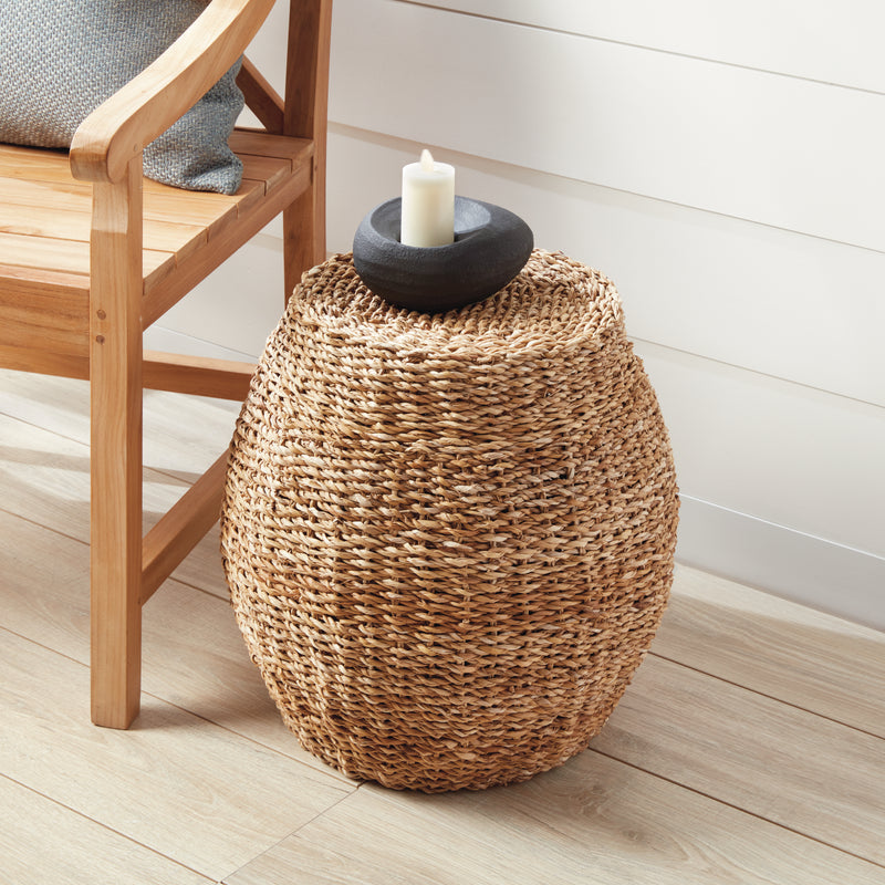 Woven brown cube stool on white porch with wood floor next to a wooden chair