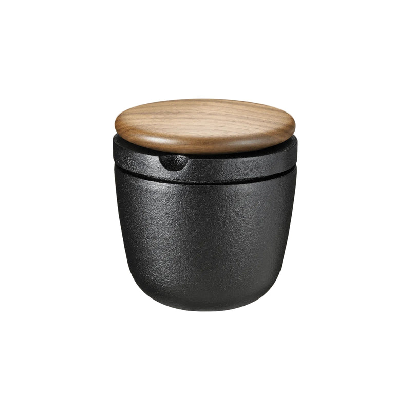 Black container with a wooden lid on a beige background