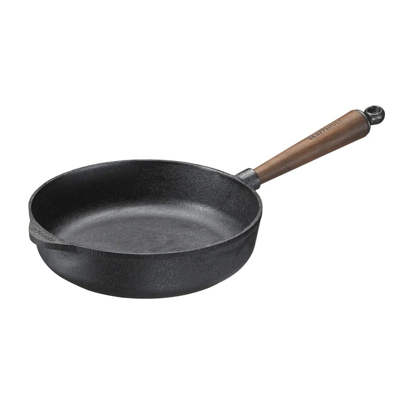 Black cast iron skillet with a wooden handle on a beige background