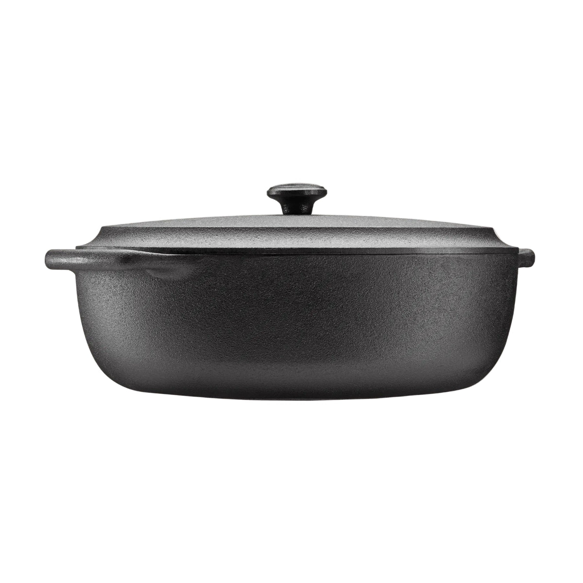 Black cast iron casserole dish with lid on a beige background