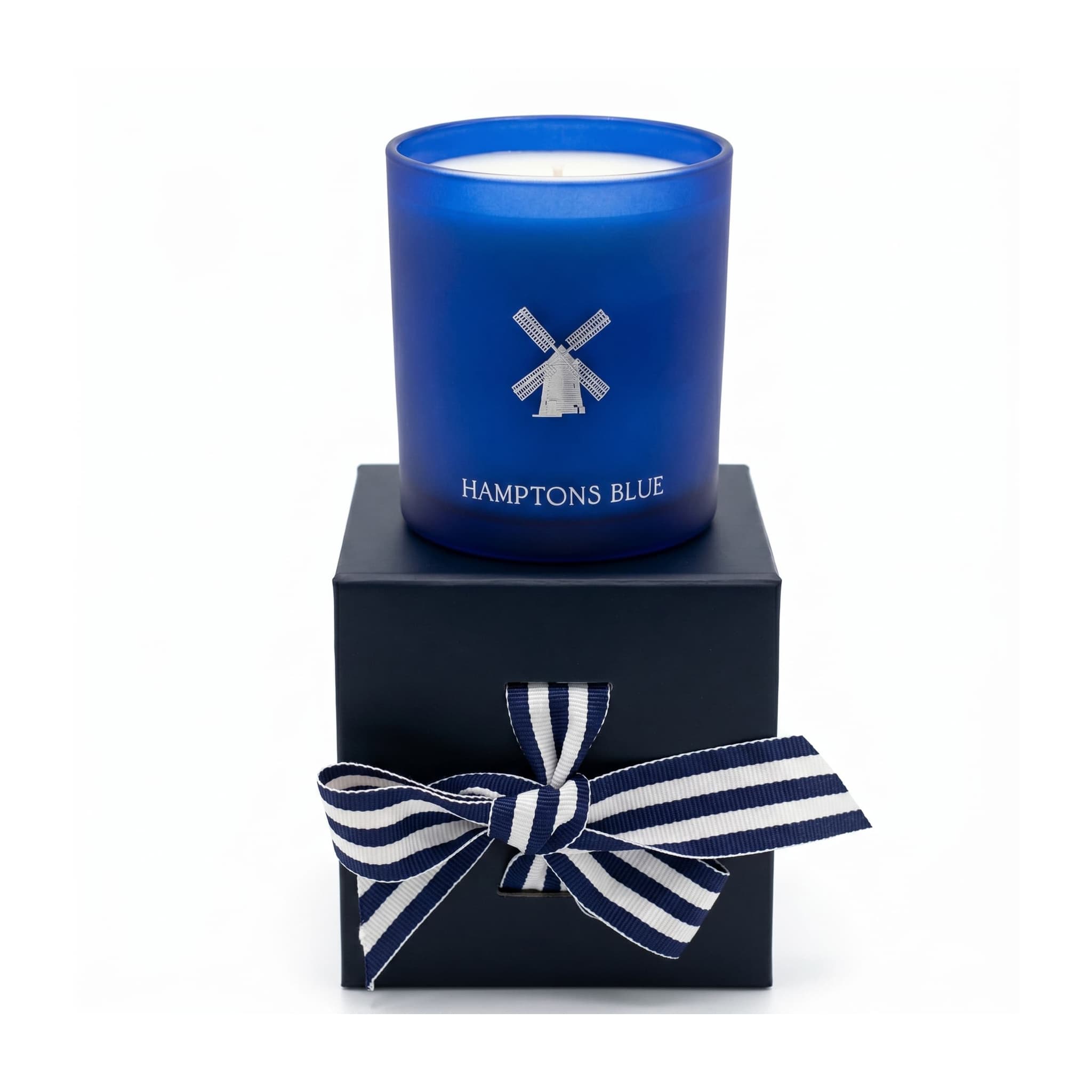 Blue candle with windmill design on a black box with a blue and white striped bow, labeled 'Hamptons Blue'.