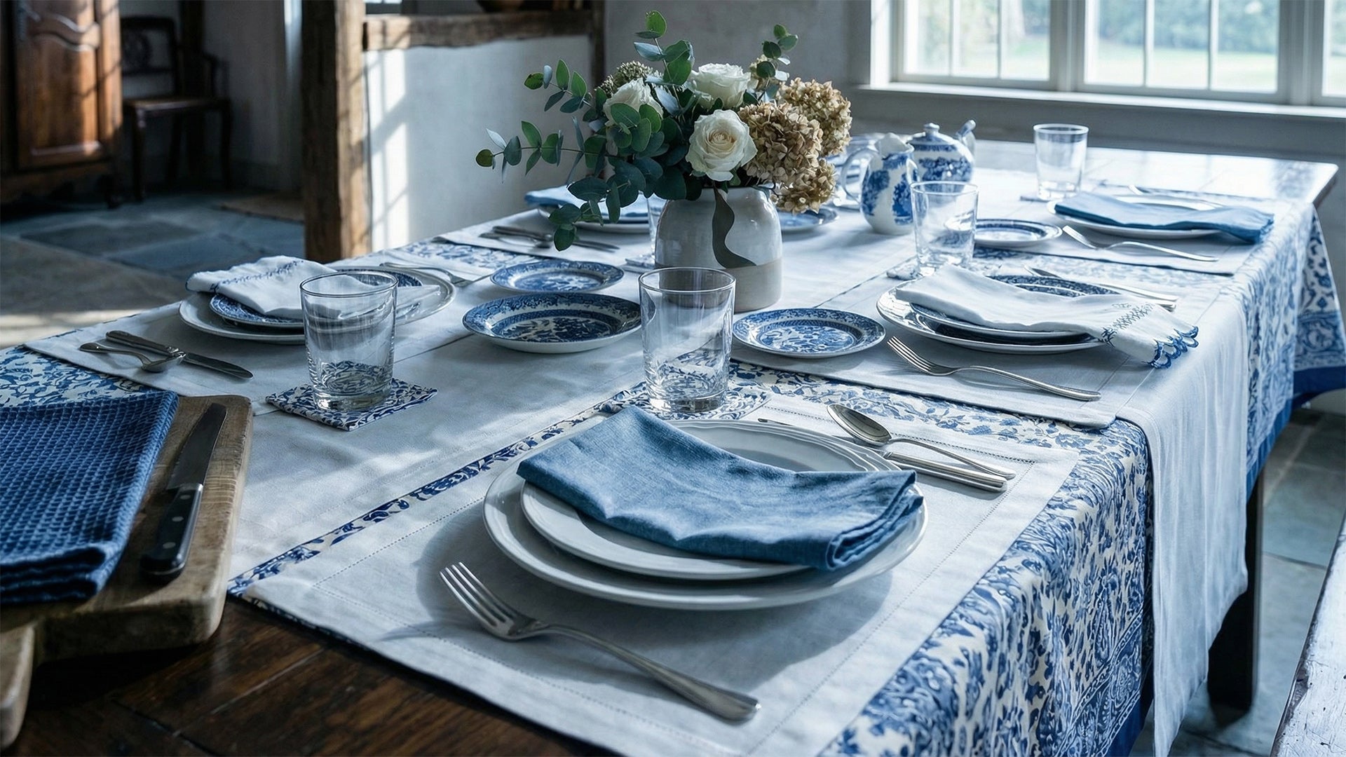 Elegant table setting with blue and white theme in a room with large windows.