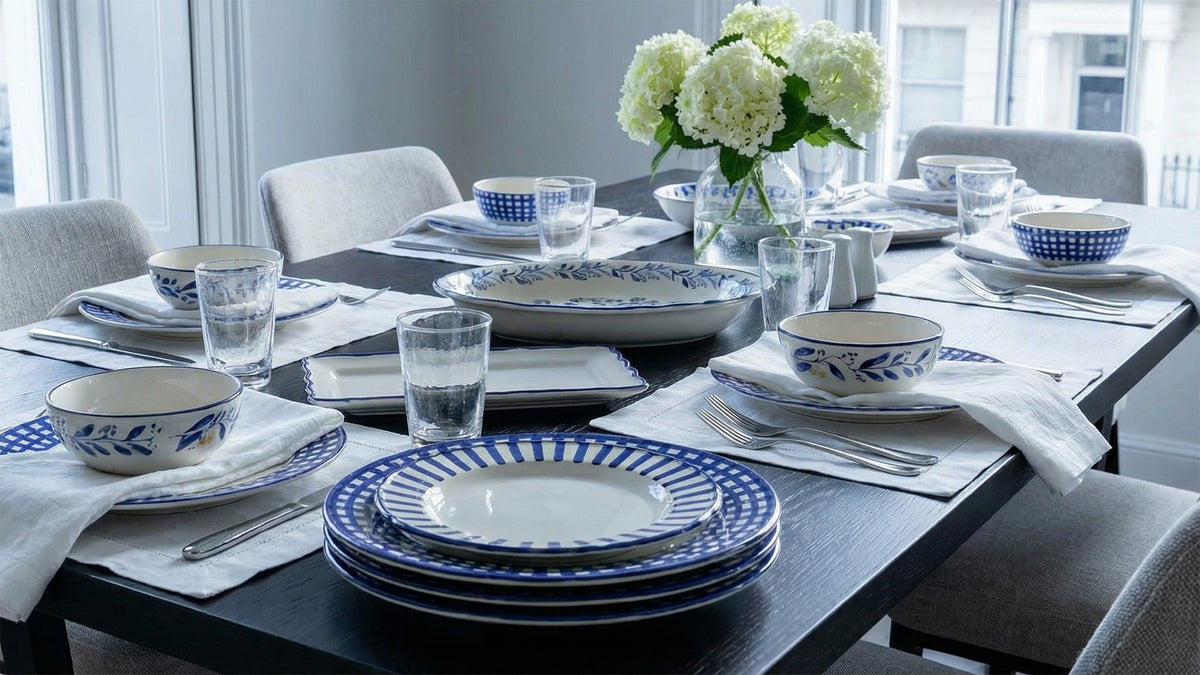 Dining table set with blue and white瓷器, glasses, and flowers in a modern kitchen.