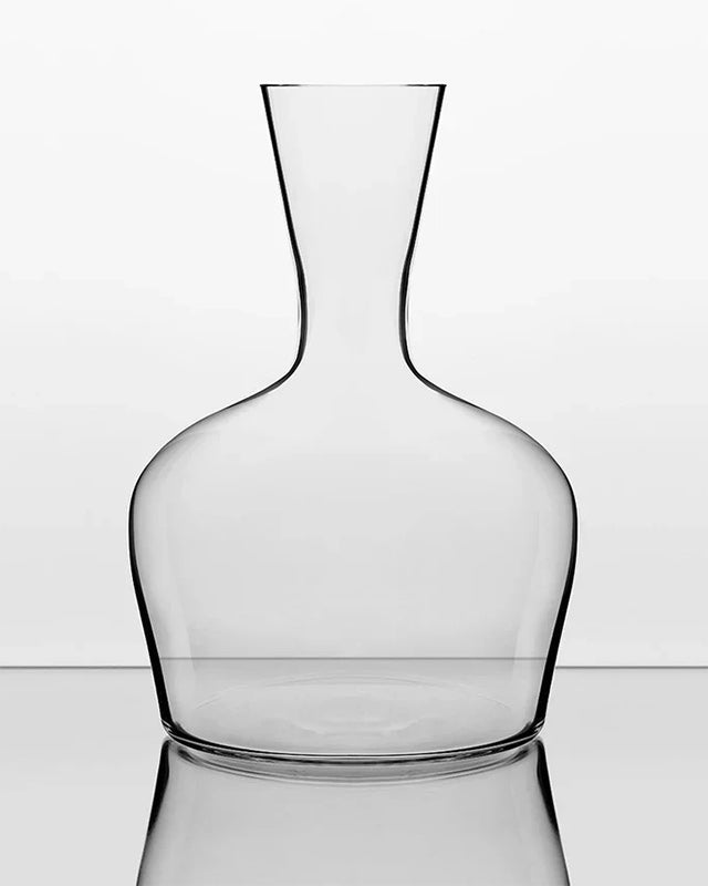 Clear glass decanter on a reflective surface with a white background