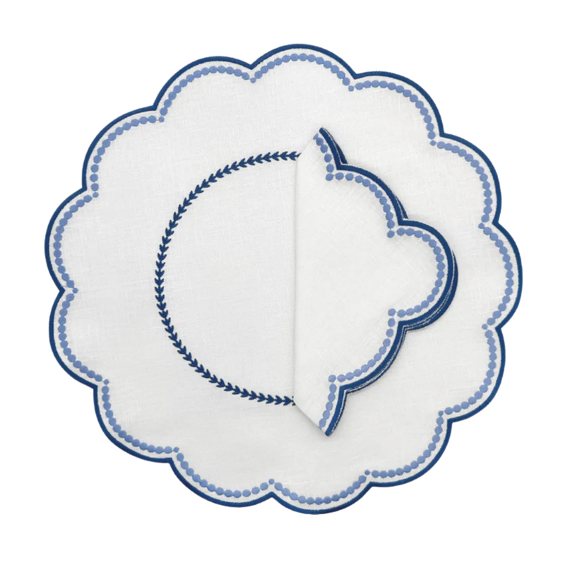 A set of four folded white linen napkins with a blue floral pattern.