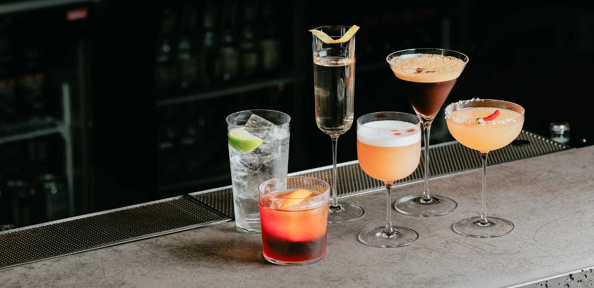 Assorted cocktails on a bar counter with a dark background