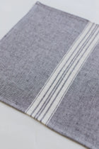 Gray linen placemat with white stripes on a light gray background