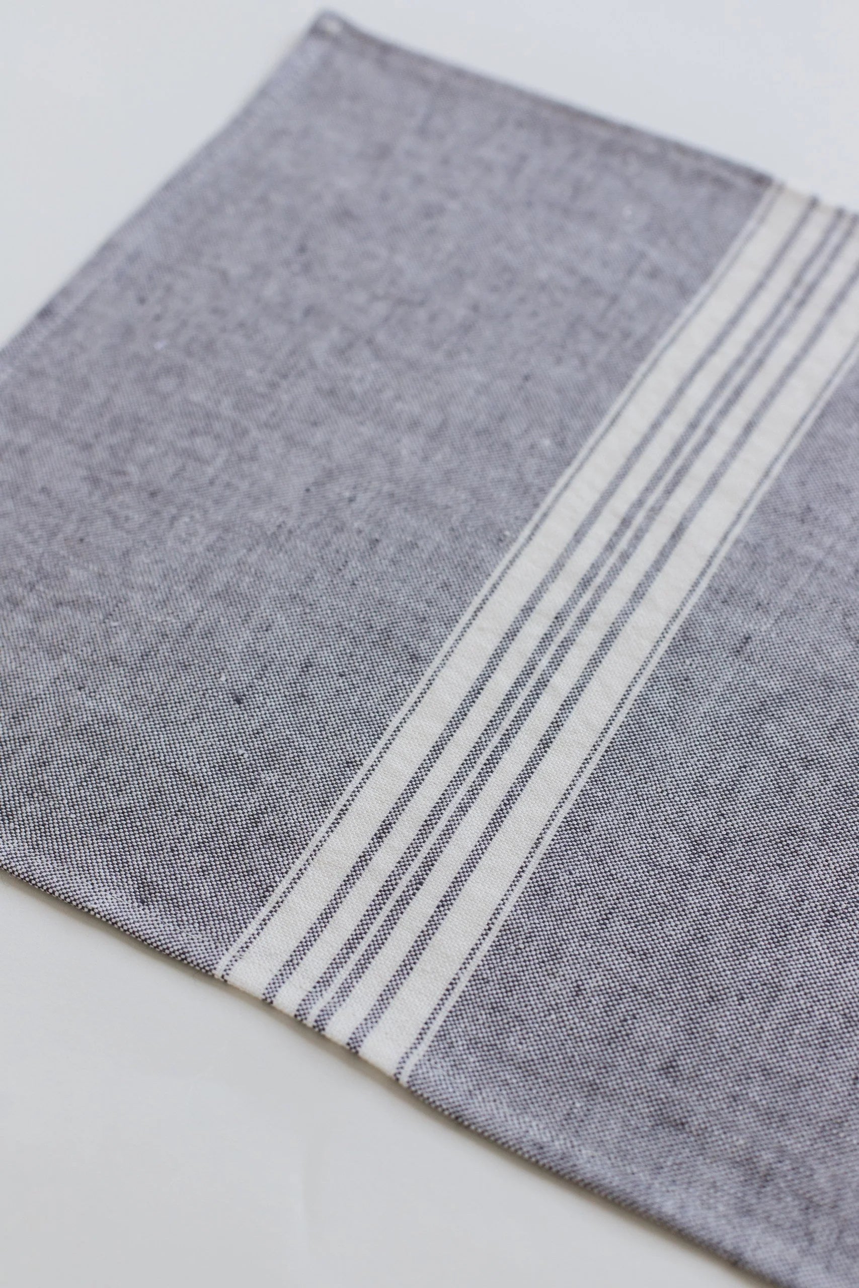 Gray linen placemat with white stripes on a light gray background
