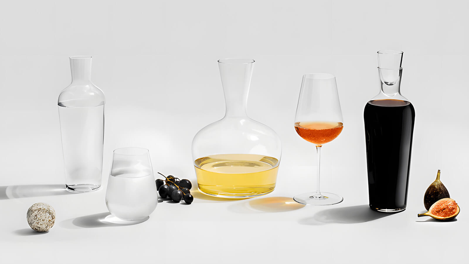 Set of glass decanters and a wine glass on a light gray background