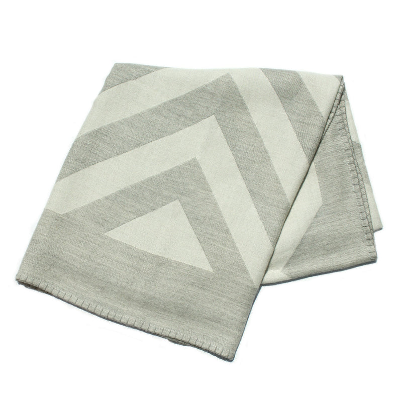 Folded gray and white geometric patterned blanket on a white background