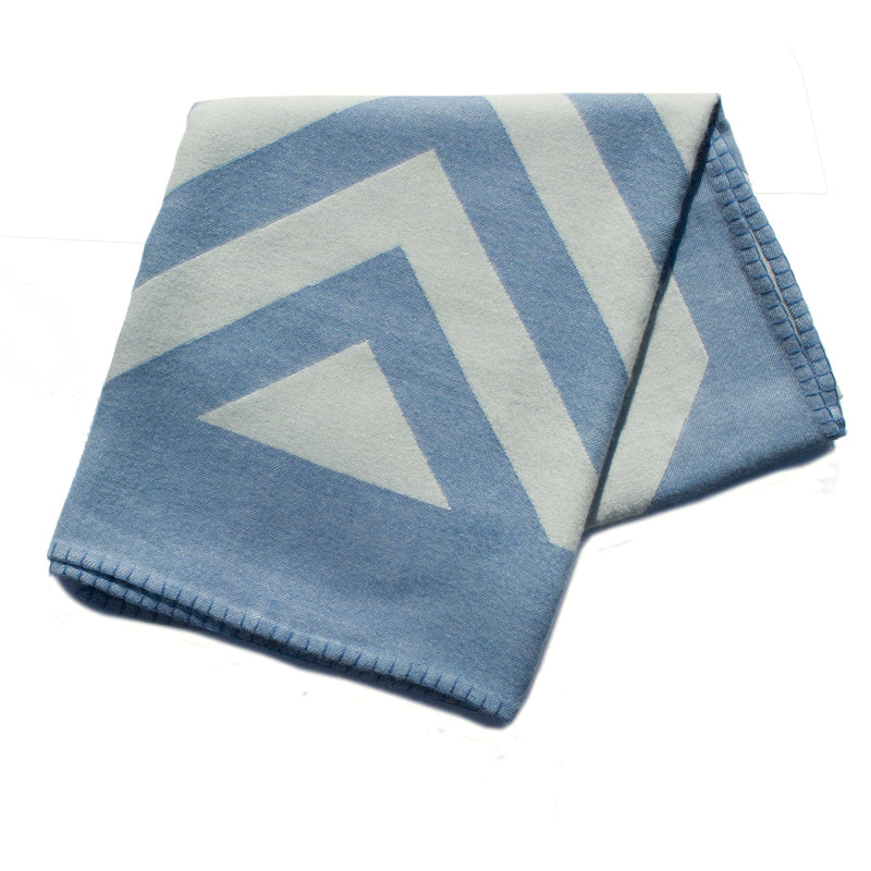 A folded throw with a chevron pattern in blue and white colors, featuring a whip stitch edge.