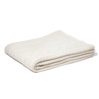 A folded beige cable knit throw made of baby alpaca wool.