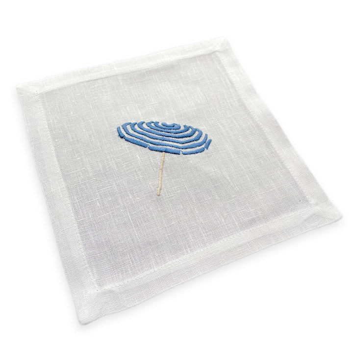 White linen cocktail coaster with a blue umbrella design on a white background