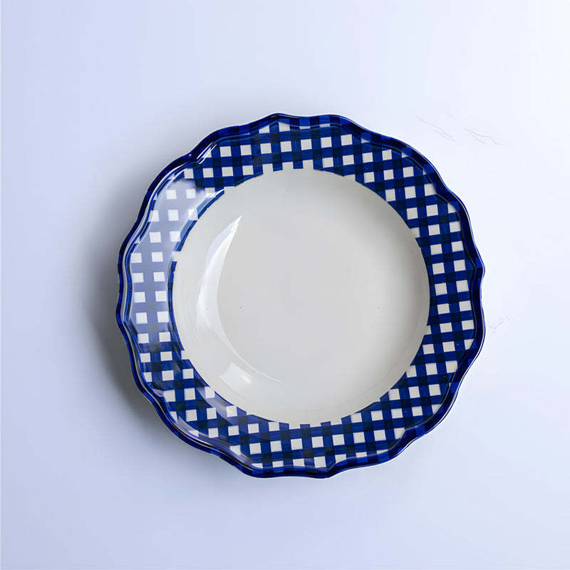 White plate with blue checkered rim on a light gray background