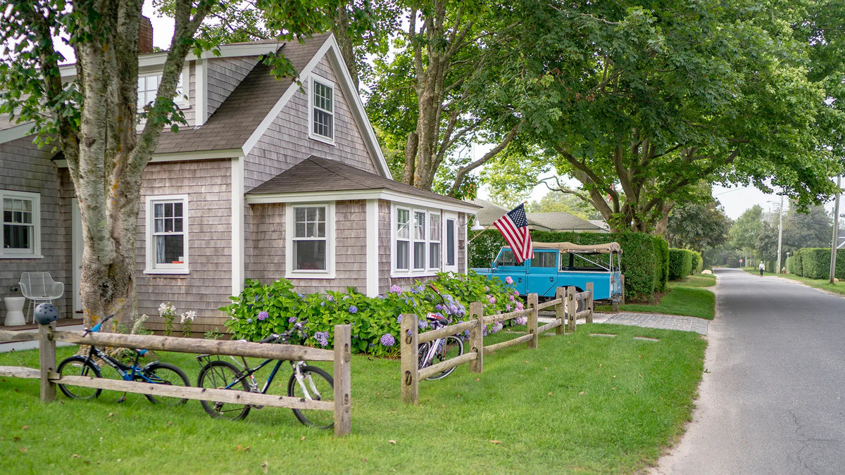 Cottage with a garden and parked car on a residential street