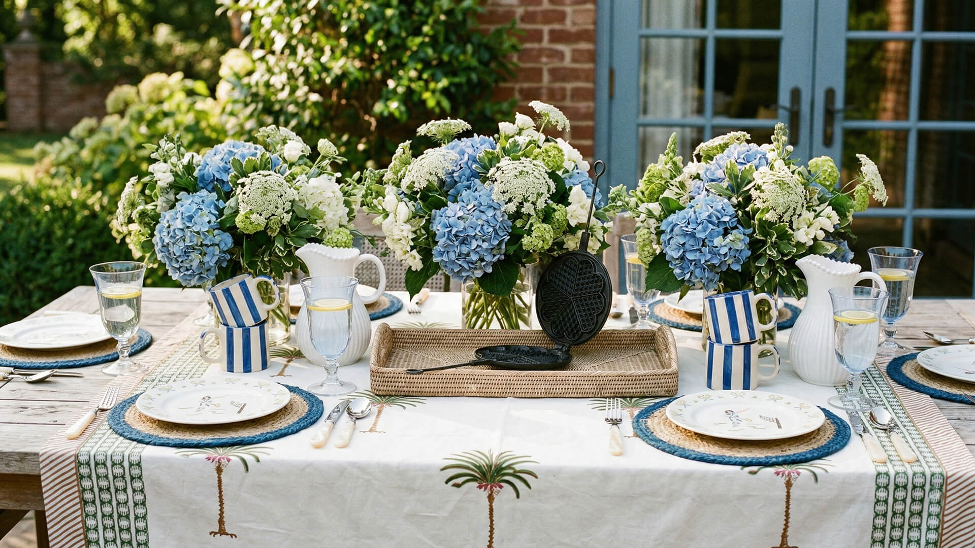 Outdoor table setting with floral centerpieces and tableware.