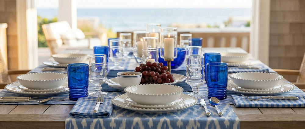 Dining table set with blue and white tableware, glasses, and fruit on a patio.