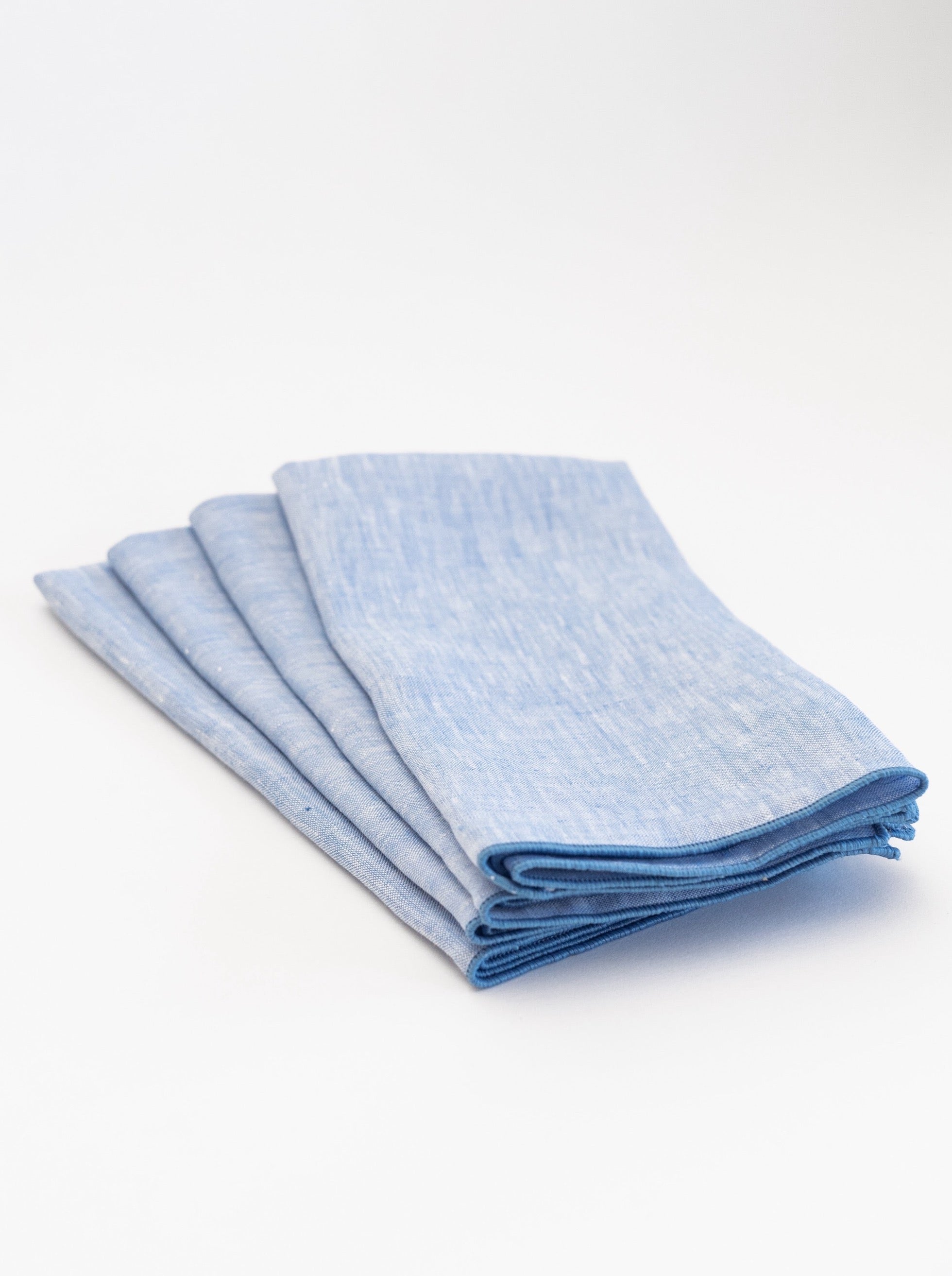 Set of four folded blue napkins on a white background