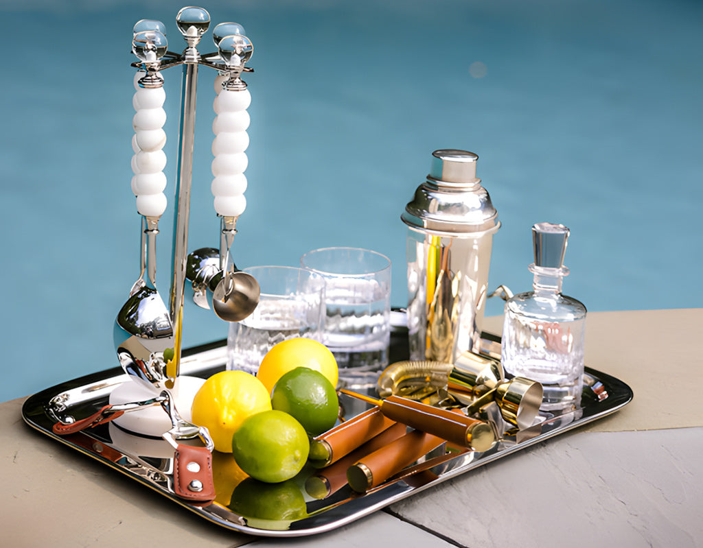 Bar tray with cocktail shaker, glasses, and bar tools on a blue background