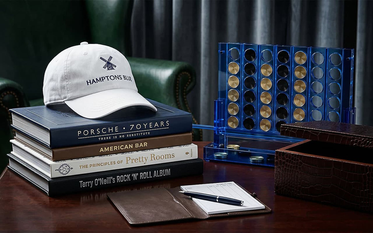 Stack of books with a cap, pen, and board game on a table