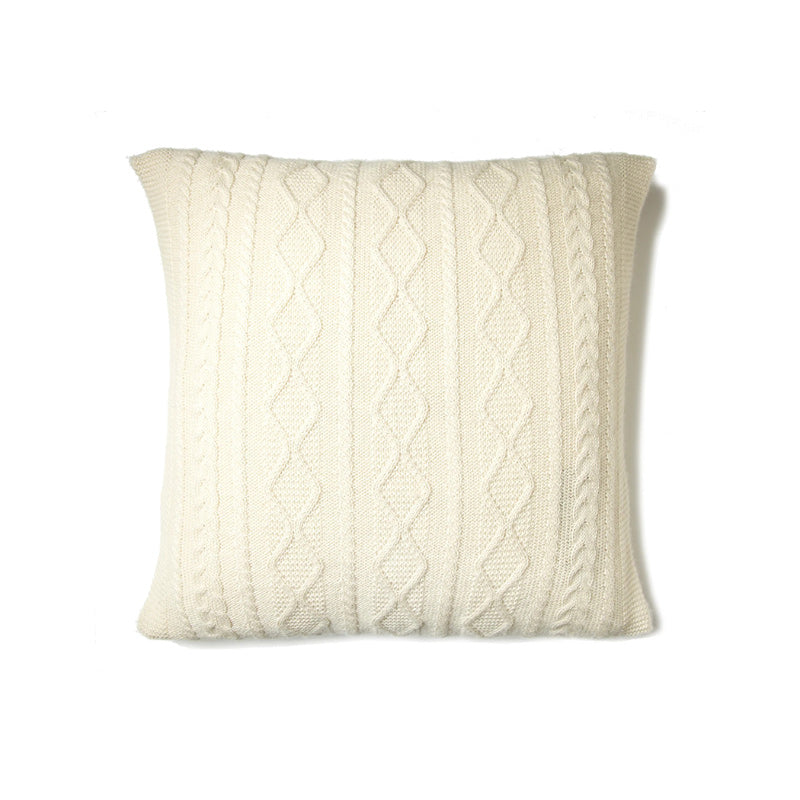 Knitted pillow with cable pattern on a white background