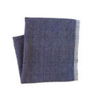 Two blue napkins on a beige surface with a fork and decorative items.
