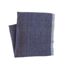 Two blue napkins on a beige surface with a fork and decorative items.
