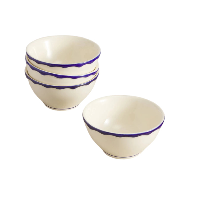 Set of 4 white ceramic bowls with blue rims on a beige surface