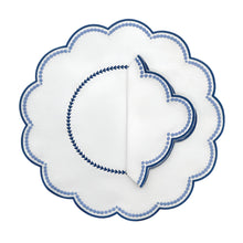 A set of four round placemats with blue scalloped edges and embroidered details in the center.