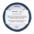 A circular decorative plaque or coaster featuring a dark blue textured border, a white center with blue lighthouse and surfboard motifs, and printed text identifying it as Montauk - 11954 with descriptive copy about coastal heritage.