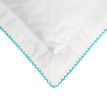 White fabric with turquoise embroidery on a white backgroun