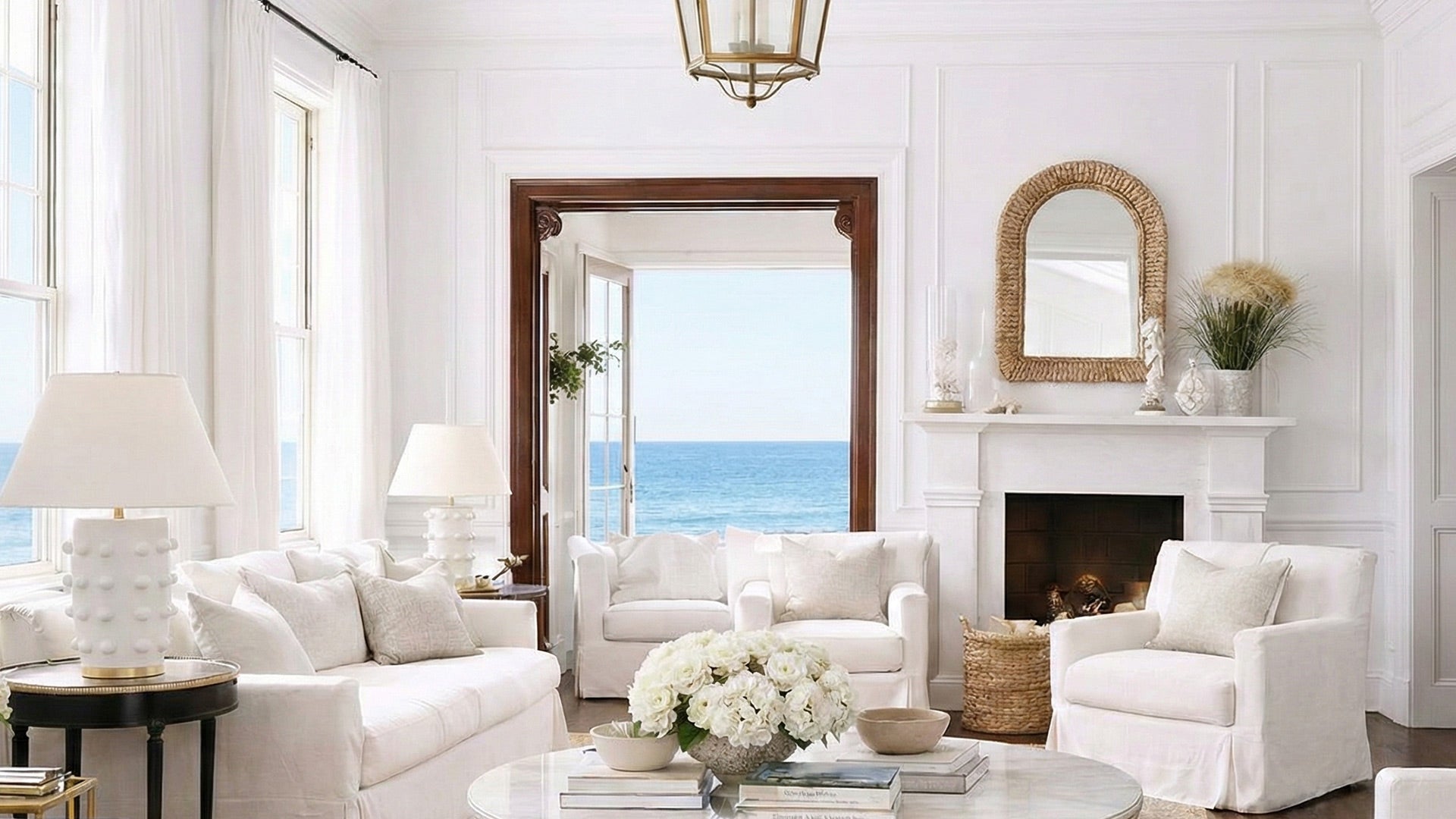 Living room with white furniture, a fireplace, and a view of the ocean.