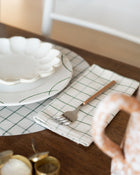 Table setting with plates, cutlery, placemat and a napkin on a wooden table.